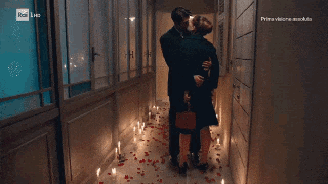 a man and woman kissing in a hallway with candles on the floor and rai hd written on the bottom