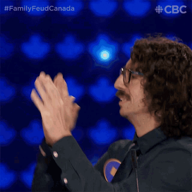 a blurred image of a man giving another man a high five with the words family feud canada on the bottom
