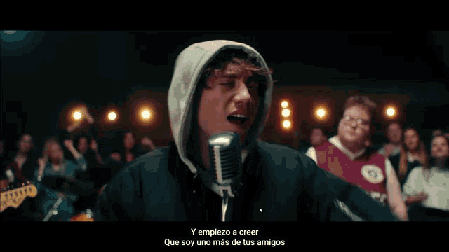 a man singing into a microphone with the words y empiezo a creer