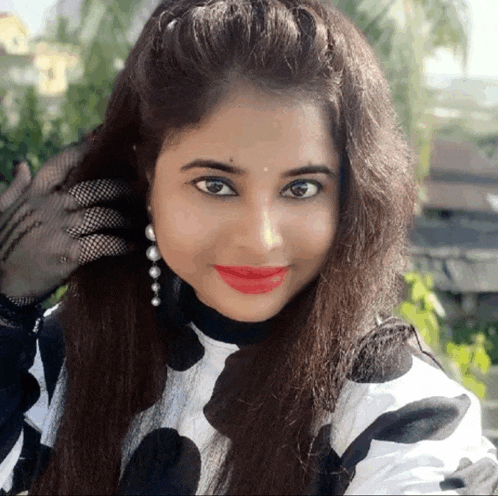 a woman wearing a black and white polka dot shirt and red lipstick is smiling