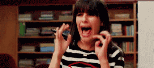 a woman in a striped shirt is screaming and holding a pen in her hand .