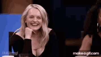 a woman is smiling while sitting at a table with make a gif.com on the bottom right
