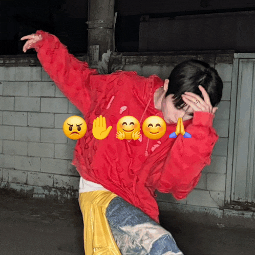 a person wearing a red sweatshirt with emojis on it covering their face