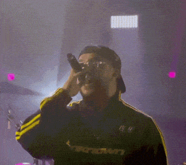 a man singing into a microphone wearing a jacket that says ' unknown ' on it