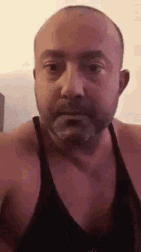 a shirtless man with a beard is making a funny face .