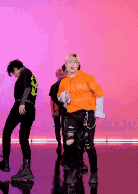a group of young men are dancing in front of a pink and purple background