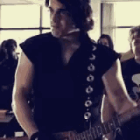 a man in a black shirt is holding a guitar in a room .