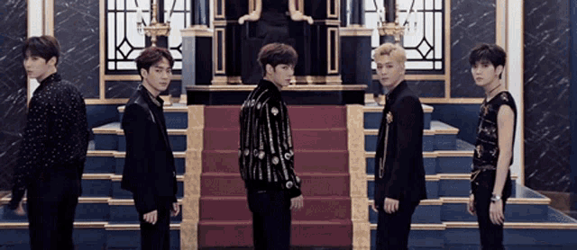 a group of young men standing next to each other in front of a staircase