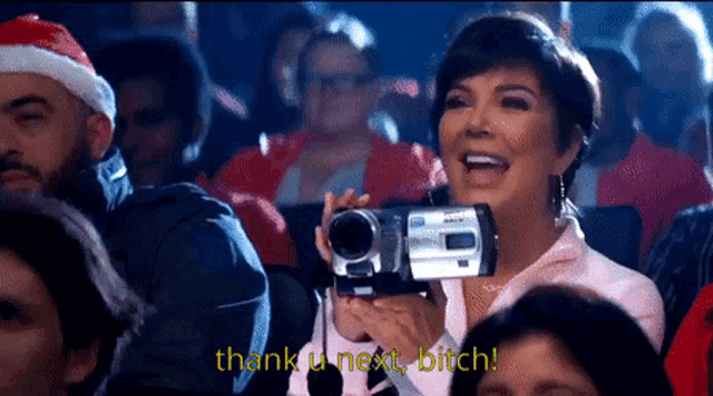 a woman is holding a video camera with the words thank u next bitch below her