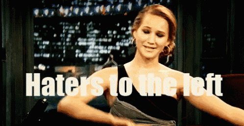 a woman is dancing in front of a sign that says haters to the left .