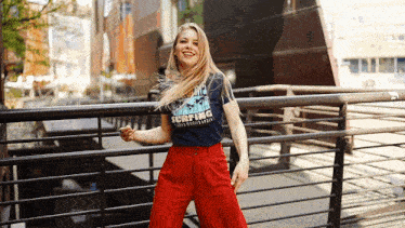 a woman wearing a shirt that says surfing is standing next to a railing