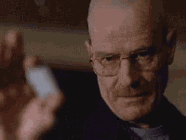 a close up of a man wearing glasses holding a bottle of pills .