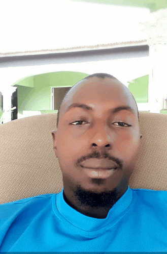 a man in a blue shirt sits on a chair