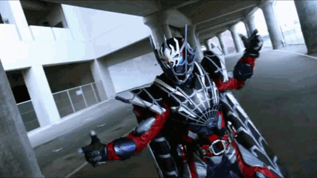 a man in a black and red costume is standing in front of a building .