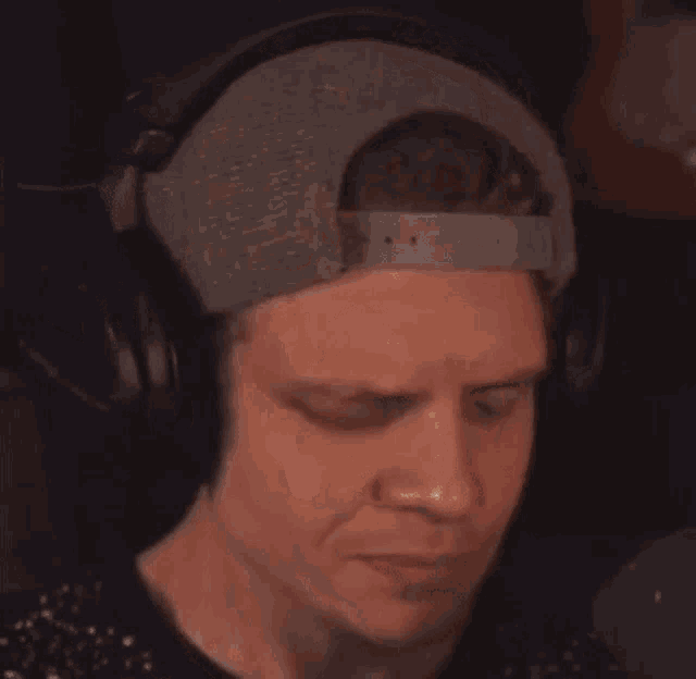 a man wearing headphones and a baseball cap is eating a piece of food .
