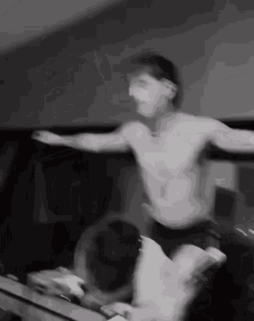 a man without a shirt is dancing in front of a mirror .