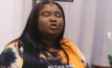 a woman in a tie dye shirt is making a funny face with her eyes closed .