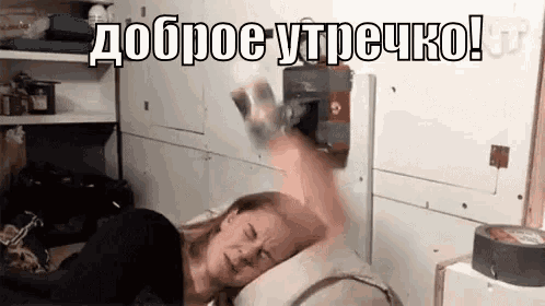 a woman is laying in bed with her head on a pillow while a person throws a bottle of water at her .