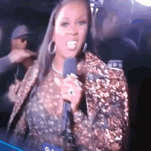 a woman is holding a microphone and smiling while wearing a leopard print jacket .