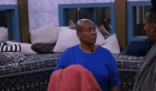 a woman in a blue shirt is sitting on a couch with pillows