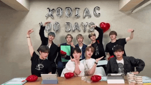 a group of young men are posing for a picture in front of a wall that says xodiac 100 days
