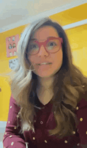 a woman wearing glasses and a polka dot shirt looks at the camera .