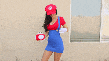 a woman in a super mario costume is holding a mushroom