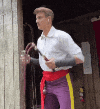 a man in a white shirt and purple pants is holding a sword