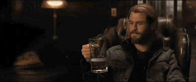a man sitting in a chair holding a beer mug