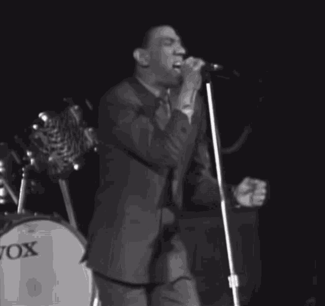 a man singing into a microphone in front of a drum that says vox