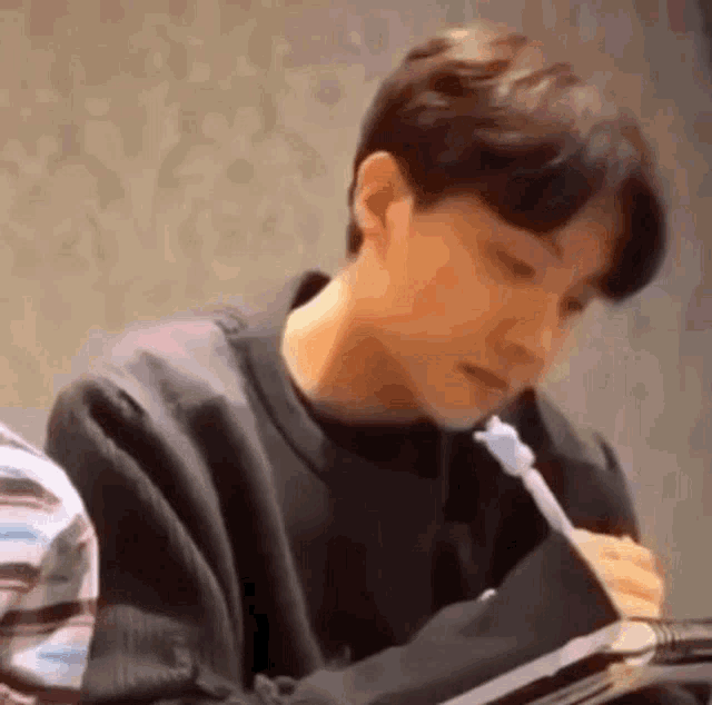 a man is sitting at a table with a pen in his mouth .