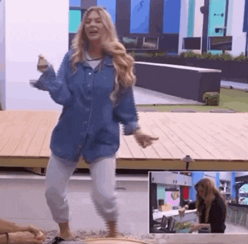 a woman in a denim shirt and white pants is dancing in a room .
