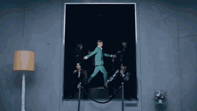 a group of people are standing in front of a painting of a man in a suit