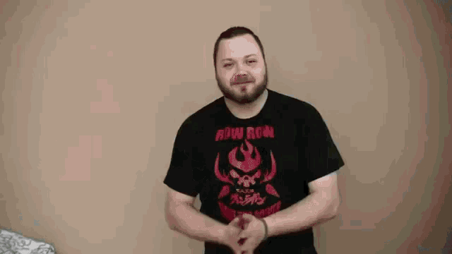 a man in a black shirt is standing in front of a wall .