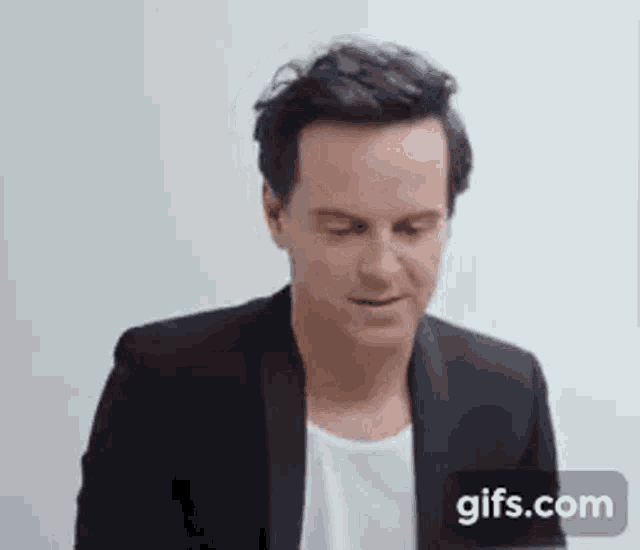 a man in a black suit and white shirt is looking down .