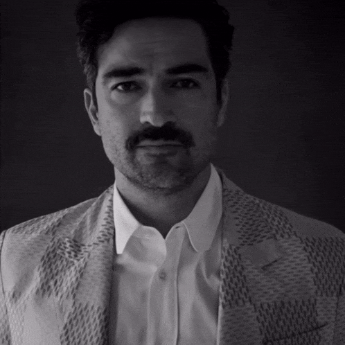 a man with a beard and mustache is wearing a white shirt and a patterned jacket