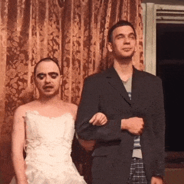 a man in a suit stands next to a woman in a dress