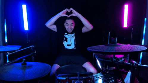 a man with a tattoo on his arm is playing drums and giving a thumbs up