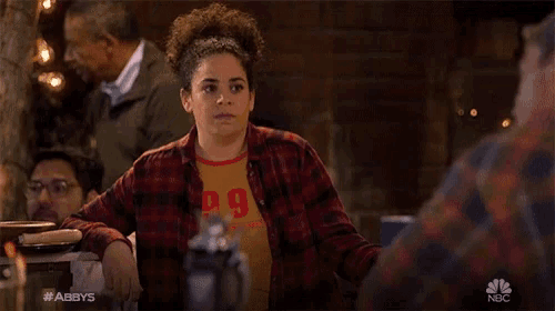 a woman wearing a plaid shirt with the number 9 on it sits at a table