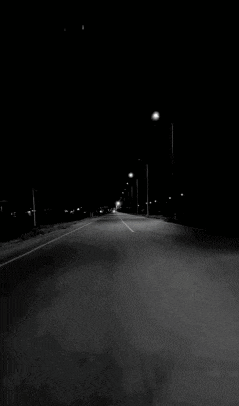 a black and white photo of a car driving down a street at night with the letter z in the background