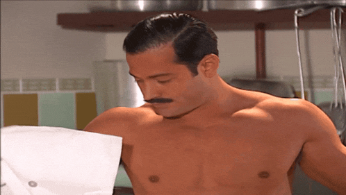 a shirtless man with a mustache is holding a chef 's apron