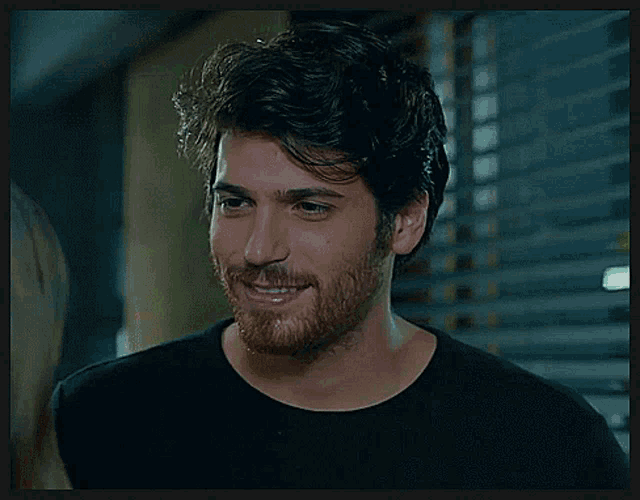 a man with a beard and a black shirt smiles