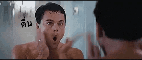a shirtless man is looking at himself in the mirror and making a surprised face .