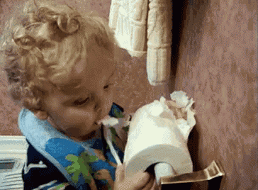 a young boy is eating a roll of toilet paper