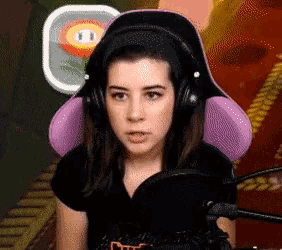 a woman wearing headphones sits in front of a microphone in front of a flower
