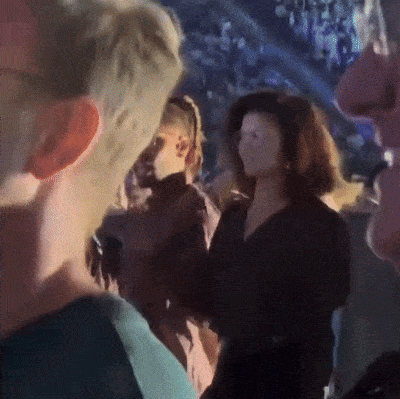 a group of people are standing in a dark room and one of them is wearing a black shirt