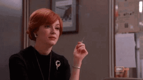 a woman with red hair is holding a pen in her hand .