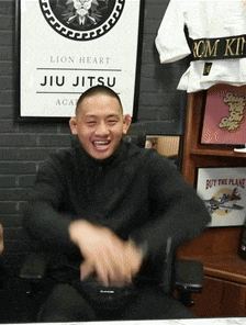 a man is sitting in front of a sign that says jiu jitsu
