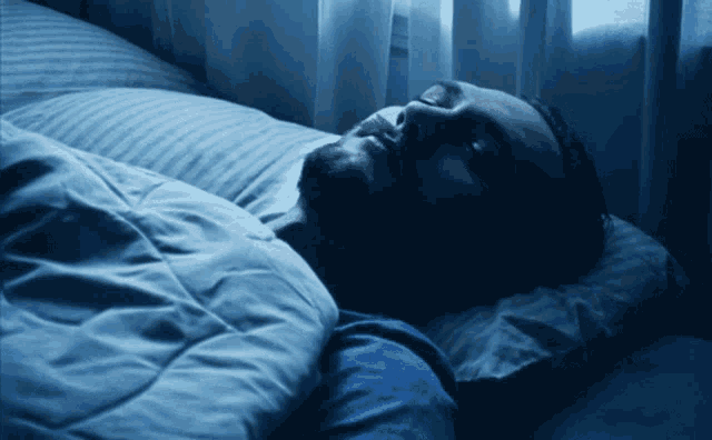 a man is sleeping with his eyes closed in a bed