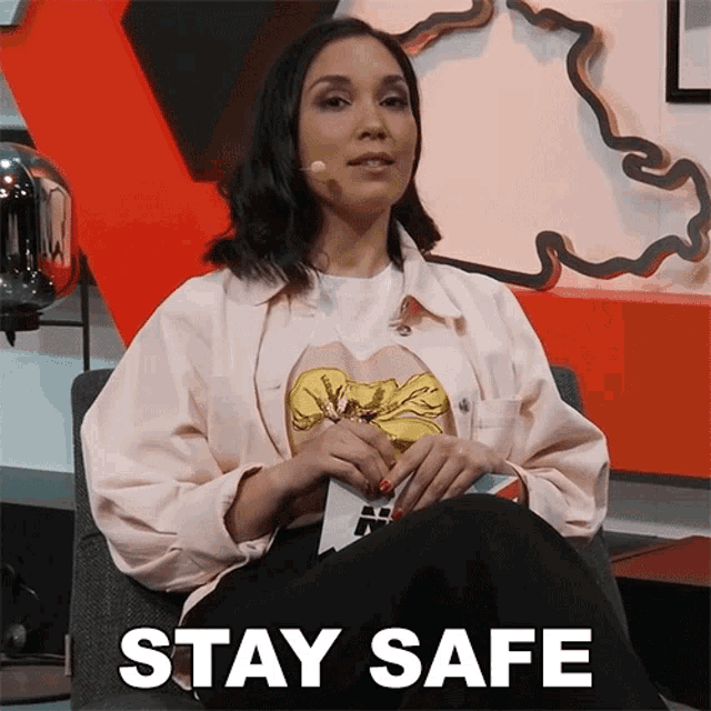 a woman in a pink jacket sits in a chair with the words " stay safe " below her